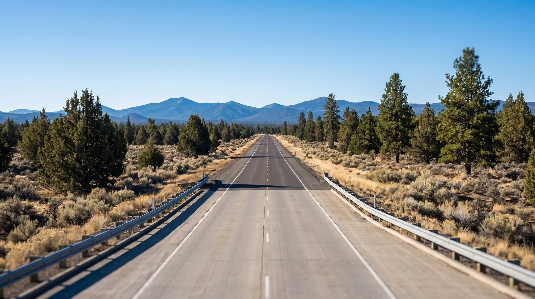 A wide western landscape at first light with a highway running toward distant mountains