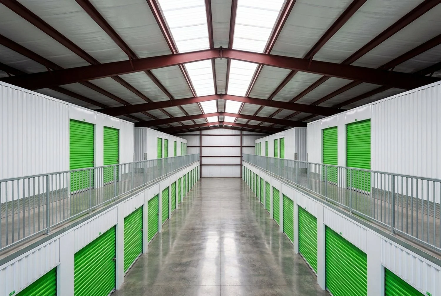 Inside a pre-engineered metal building: the red primary steel frame spans overhead while cold-formed steel partition walls form storage units on two levels below