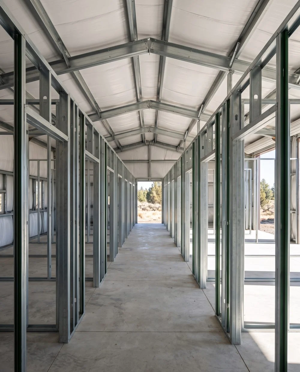 A long run of identical cold-formed steel storage unit frames repeating away inside a steel shell